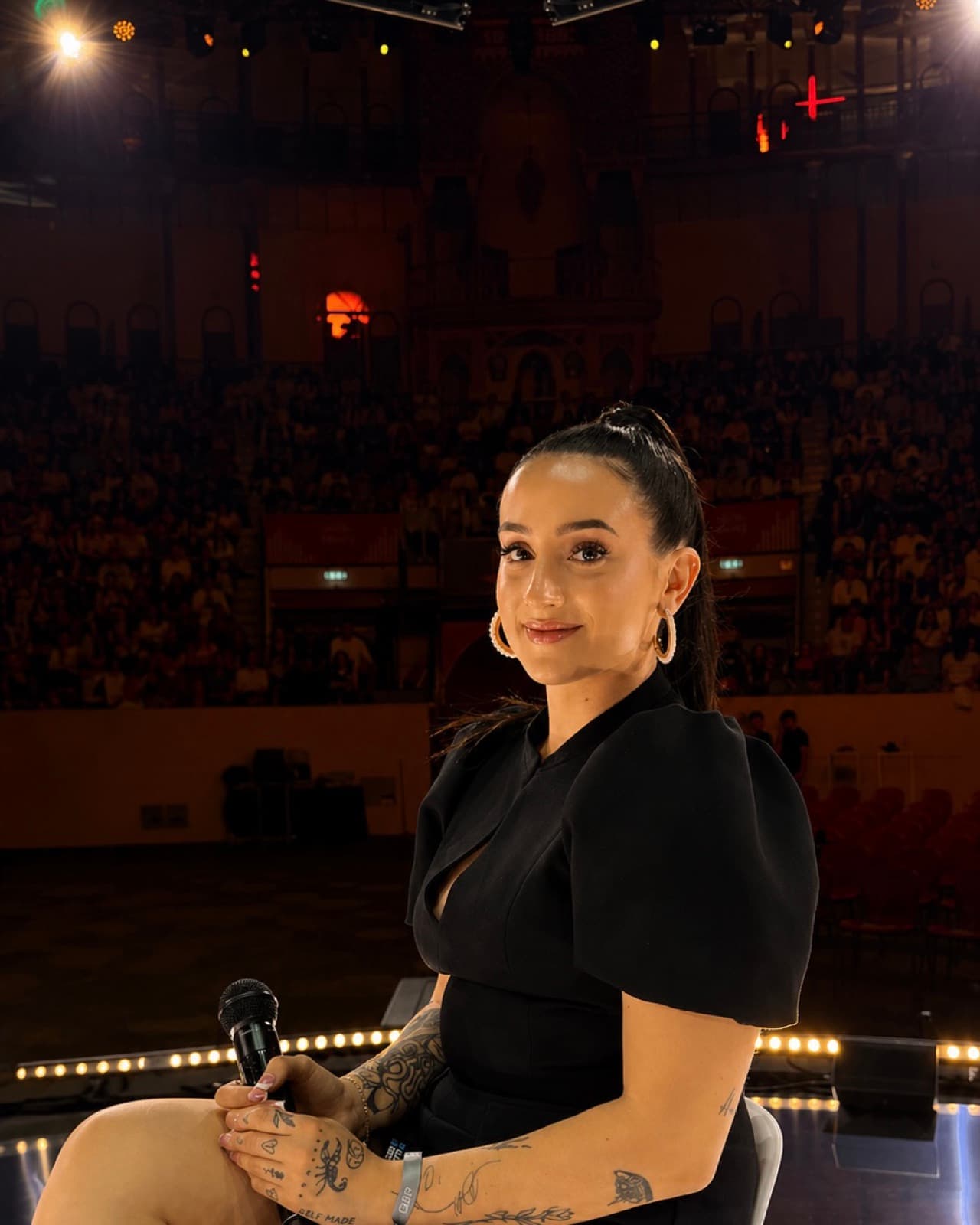 Miranda holding a microphone on stage in Europe in front of a packed 4,000 person arena